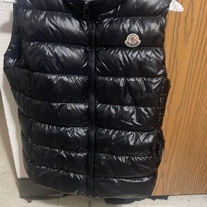 Sleeveless nylon satin vest in black. Two way zip closure at front.